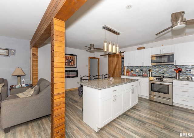 kitchen with white cabinets, appliances with stainless steel finishes, a kitchen island, and hanging light fixtures