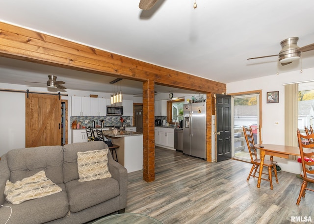 living room featuring a barn door, ceiling fan, and wood-type flooring