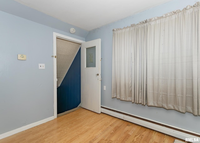 unfurnished room with a baseboard radiator and wood-type flooring