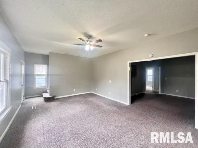 unfurnished room featuring a textured ceiling, dark colored carpet, and ceiling fan