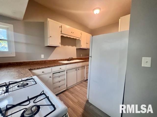 kitchen featuring white cabinetry, white appliances, sink, and light hardwood / wood-style flooring