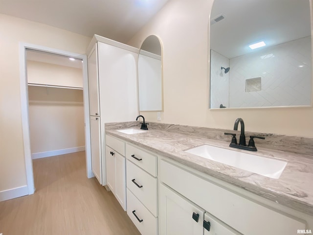 bathroom with hardwood / wood-style flooring, vanity, and a tile shower