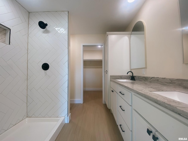 bathroom featuring hardwood / wood-style floors, vanity, and tiled shower