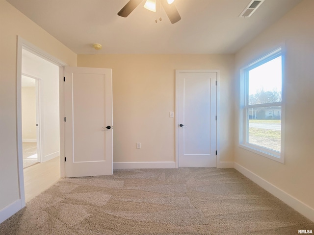 carpeted spare room featuring plenty of natural light and ceiling fan