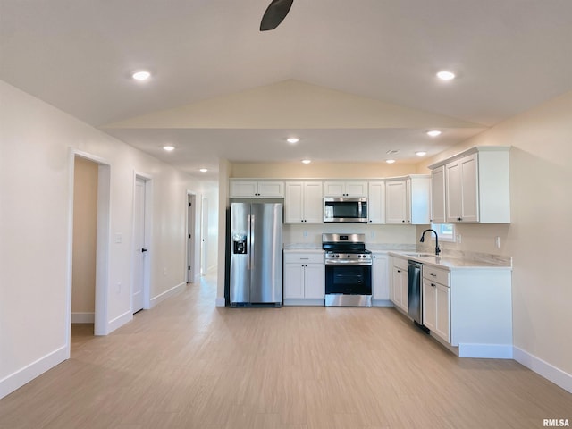 kitchen with appliances with stainless steel finishes, sink, light hardwood / wood-style flooring, white cabinets, and lofted ceiling