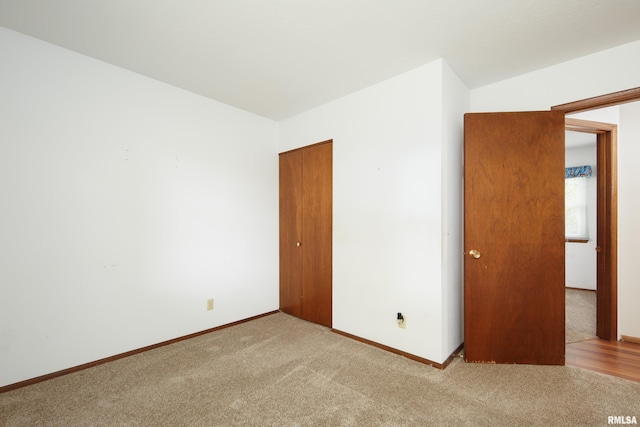 unfurnished bedroom featuring light carpet and a closet