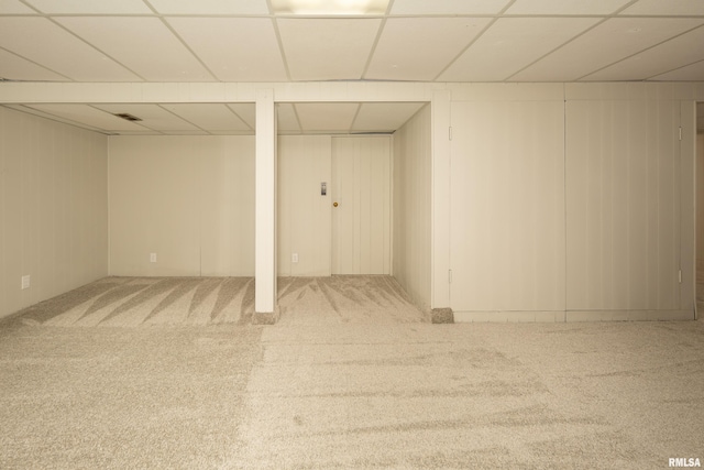 basement featuring a paneled ceiling and carpet