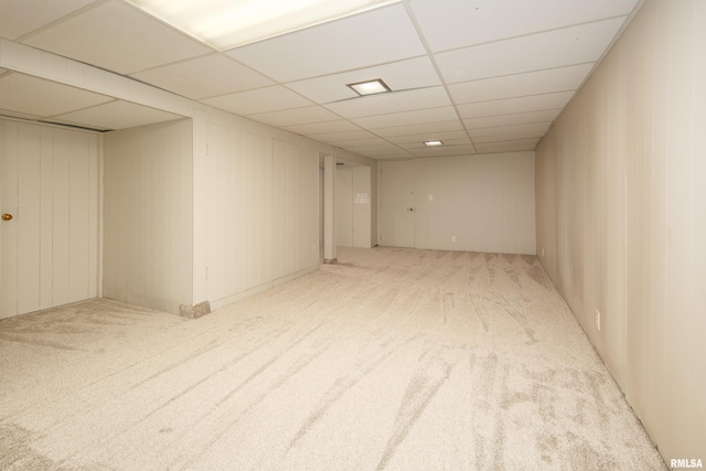 basement featuring light colored carpet and a paneled ceiling