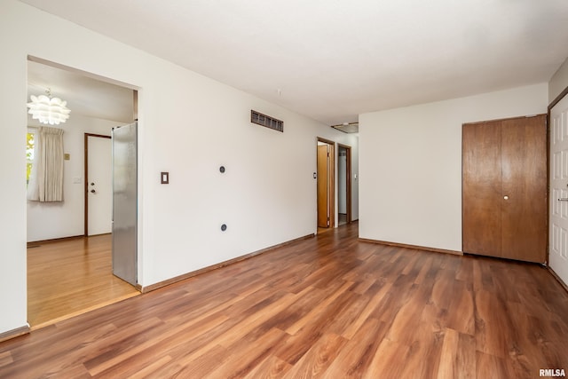 unfurnished bedroom featuring hardwood / wood-style flooring and a notable chandelier