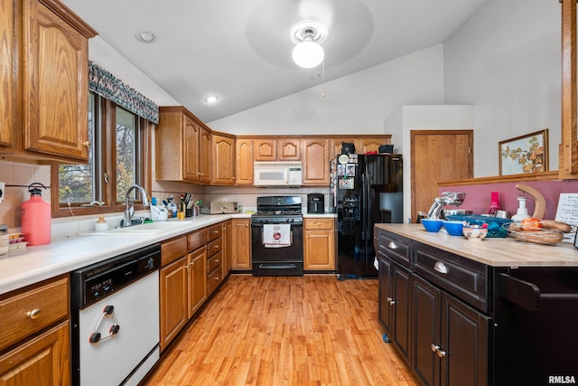 kitchen featuring black appliances, backsplash, sink, vaulted ceiling, and light hardwood / wood-style floors