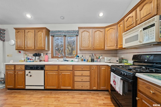 kitchen with backsplash, white appliances, sink, and light hardwood / wood-style flooring