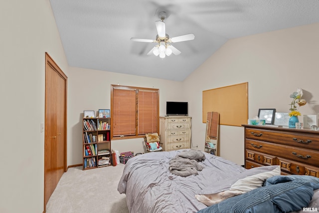 bedroom with a textured ceiling, light colored carpet, ceiling fan, and vaulted ceiling