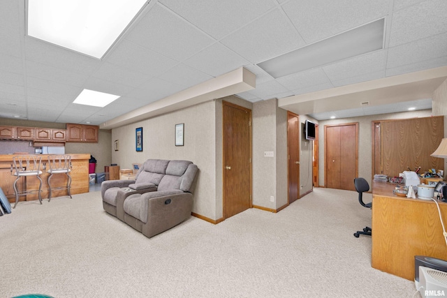 carpeted living room featuring a paneled ceiling and indoor bar