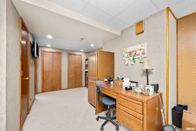 home office featuring a paneled ceiling, built in desk, and light colored carpet