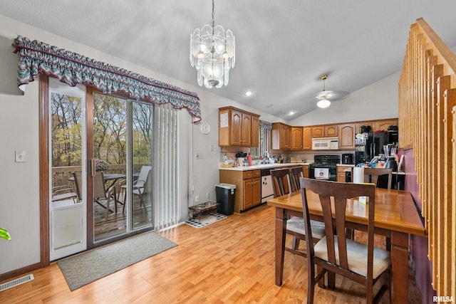 kitchen with light hardwood / wood-style floors, ceiling fan with notable chandelier, decorative light fixtures, black gas stove, and vaulted ceiling