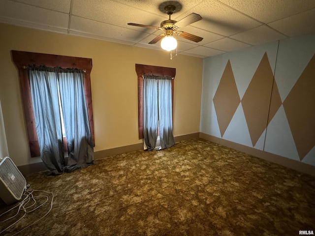 carpeted spare room featuring a paneled ceiling and ceiling fan