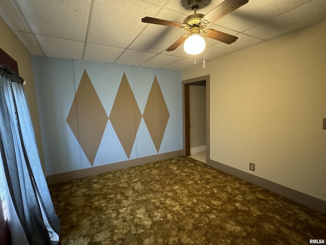 empty room with a paneled ceiling, ceiling fan, and carpet floors