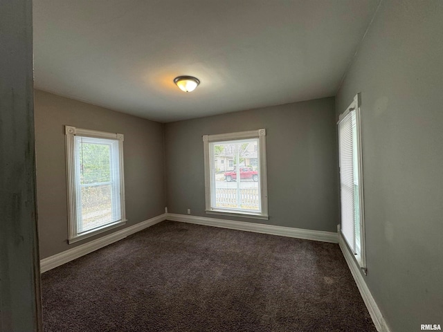 spare room with a healthy amount of sunlight and dark carpet