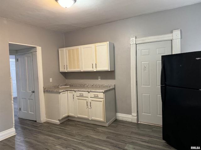 kitchen with white cabinetry, black fridge, and dark wood-type flooring