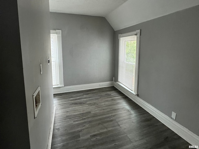 empty room with dark hardwood / wood-style flooring and vaulted ceiling