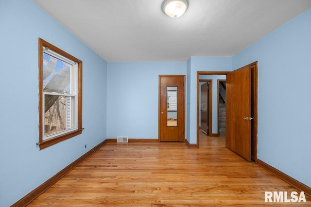 empty room with plenty of natural light and light hardwood / wood-style flooring