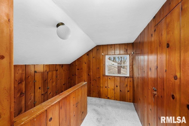 bonus room with light carpet, vaulted ceiling, and wooden walls