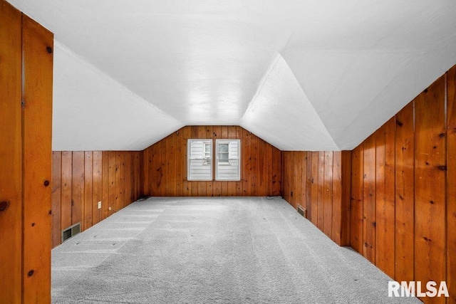 additional living space featuring lofted ceiling, light carpet, and wooden walls