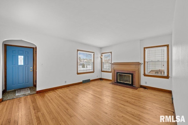 unfurnished living room featuring light hardwood / wood-style flooring and a brick fireplace