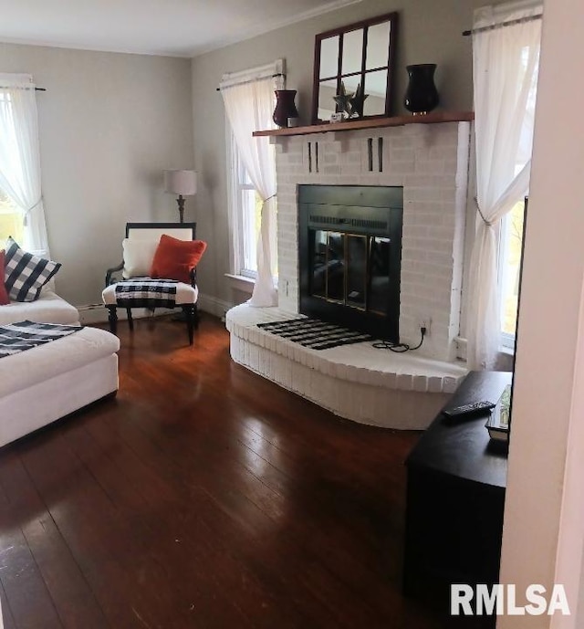 living room with a brick fireplace, wood-type flooring, and a healthy amount of sunlight