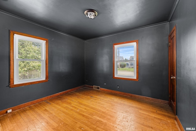 unfurnished room with plenty of natural light, light hardwood / wood-style floors, and crown molding