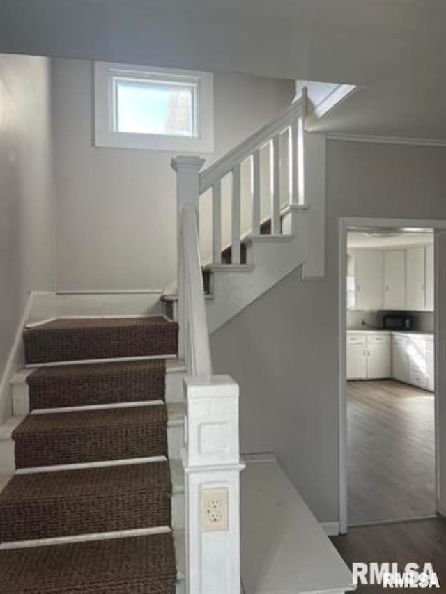 stairs featuring wood-type flooring and ornamental molding