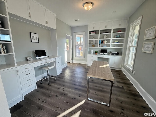 office area featuring dark wood-type flooring, built in study area, visible vents, and baseboards