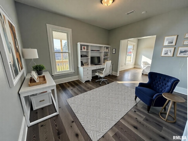 home office featuring dark wood-style flooring, visible vents, baseboards, and a healthy amount of sunlight