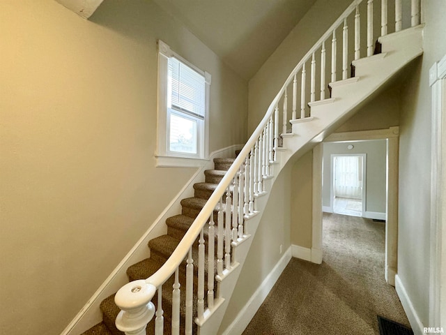 stairway with a wealth of natural light, carpet flooring, and lofted ceiling