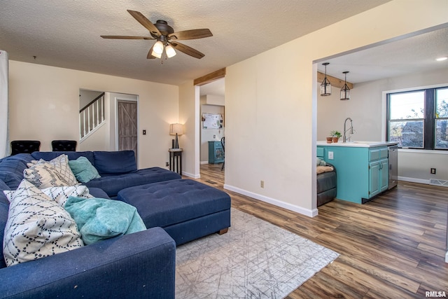 living room featuring ceiling fan, a textured ceiling, and dark hardwood / wood-style floors