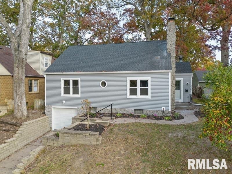 cape cod house featuring a garage and a front lawn