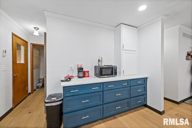 kitchen with blue cabinetry, light hardwood / wood-style flooring, white cabinets, and crown molding