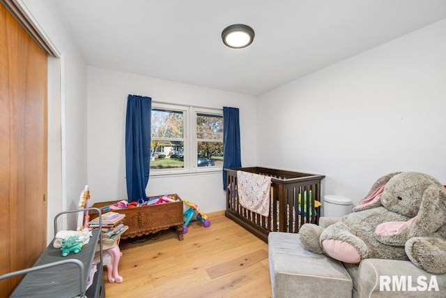 bedroom with light wood-type flooring and a nursery area