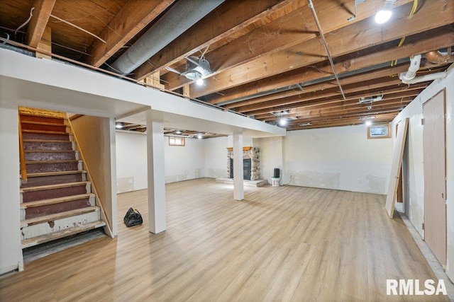 basement with a stone fireplace and light hardwood / wood-style flooring