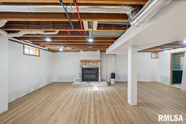 basement with hardwood / wood-style flooring and a stone fireplace