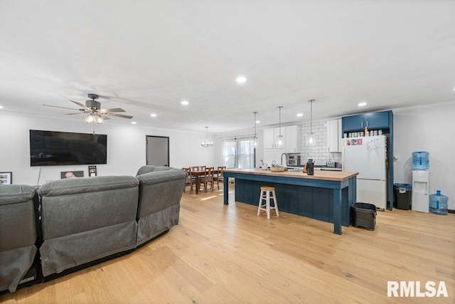 living room featuring light hardwood / wood-style floors, ceiling fan, and crown molding