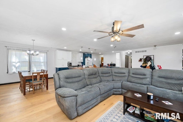 living room with ornamental molding, light wood-type flooring, and ceiling fan with notable chandelier