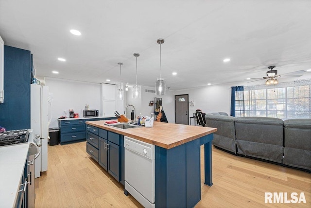 kitchen featuring appliances with stainless steel finishes, sink, an island with sink, light hardwood / wood-style floors, and blue cabinets