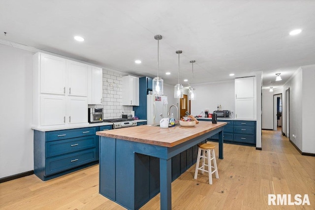 kitchen with blue cabinets, white cabinetry, light hardwood / wood-style floors, and a kitchen island with sink