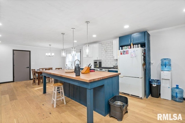 kitchen featuring a breakfast bar, an island with sink, blue cabinetry, white refrigerator, and light wood-type flooring