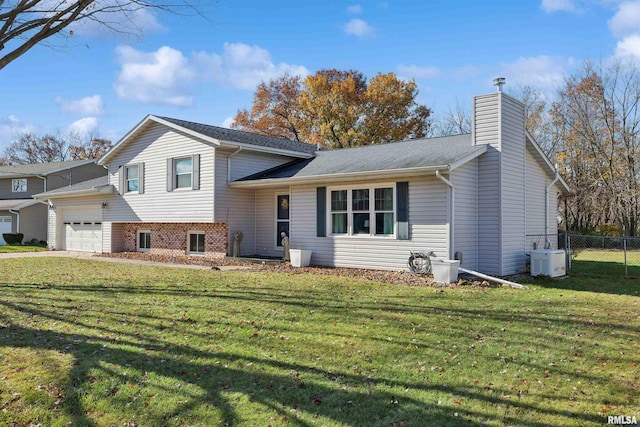 split level home with ac unit, a garage, and a front yard