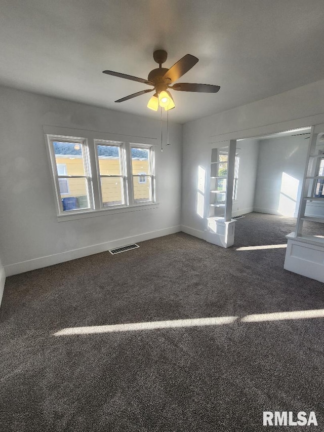 spare room with dark colored carpet and ceiling fan