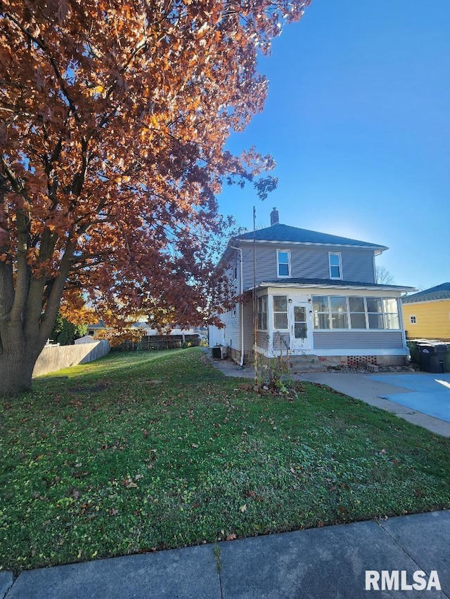 view of front of house featuring a sunroom and a front yard