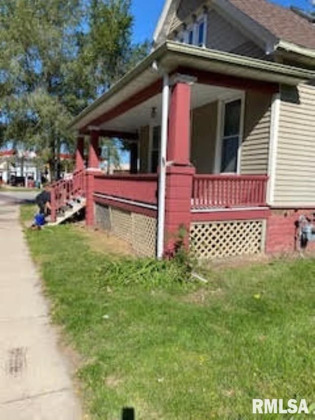 view of side of property featuring a yard and covered porch