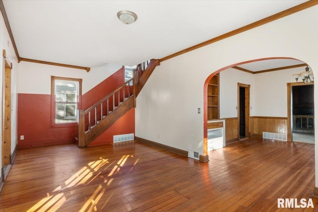 unfurnished living room with dark wood-type flooring, built in features, and ornamental molding